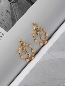 Detail of gold celestial earrings featuring sun moon and star charms on magazine