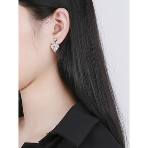 Silver heart earrings with angel relief design on a model's ear for a retro look
