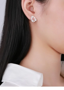 Detail of S925 sterling silver asymmetrical floral earrings worn on a woman's ear