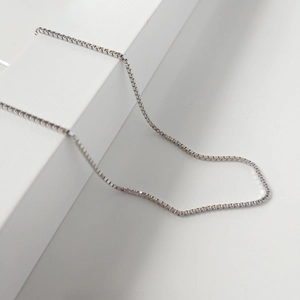 Minimalist S925 sterling silver box chain necklace displayed on a white geometric stand