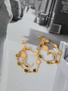 Macro view of gold S925 sterling silver earrings with celestial sun, moon, and star charms