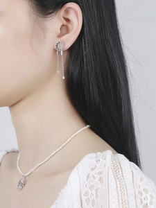 Close-up of daisy pendant and matching earrings with delicate pearl necklace on a model