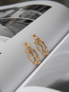 Macro detail of gold-plated celestial earrings featuring sun and moon motifs