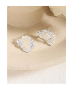 Close-up of S925 sterling silver asymmetrical flower petal stud earrings on a ceramic tray