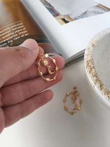 Detailed view of gold celestial hoop earrings featuring sun and moon charms on magazine
