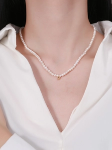 Detail of S925 sterling silver pearl necklace with a single gold bead on collarbone
