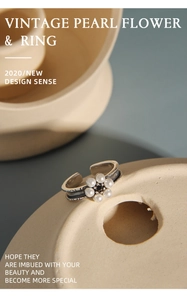 Detail of vintage flower ring with white pearls and black gemstone on a textured surface