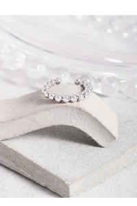 Macro shot of silver beaded open ring with mirror finish on grey textured stone