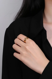 Macro side view of layered gold-plated spiral ring on model against gray background