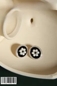 Detail of vintage oval stud earrings with black enamel and white pearl floral design