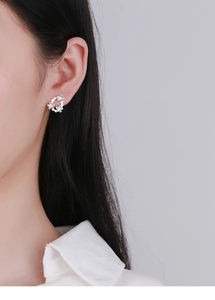 Detail view of a 925 sterling silver floral hoop earring on a model ear