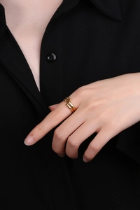Close-up of a minimalist gold layered wrap ring worn on a finger against black fabric