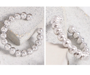 Detailed macro view of S925 sterling silver beaded C-shaped ear cuff on stone
