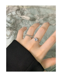 Close-up of S925 silver ring set with heart-shaped zircon and beaded band on finger