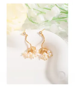Détail de boucles d'oreilles en perles avec design de branche et zircons brillants