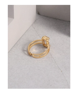 Dettaglio macro di un anello dorato regolabile con zircone rettangolare su pietra