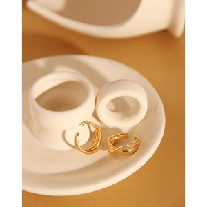 Artistic detail of gold minimalist double-layer and triple-layer rings on a ceramic tray