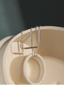 Detail of silver double-layered bar bracelet on minimalist cream ceramic props