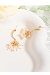 Gros plan boucles d'oreilles branche dorée avec petites perles et feuilles métalliques