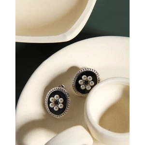 Detailed macro of oval vintage S925 silver stud earrings with black enamel and mini pearls