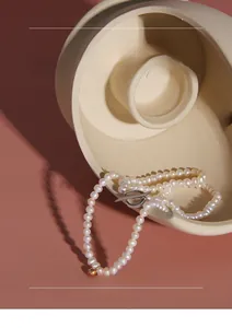 Detail of white pearl necklace with silver T-bar clasp and golden accent bead