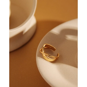 Detailed view of intertwined golden lines on minimalist open ring over ceramic plate