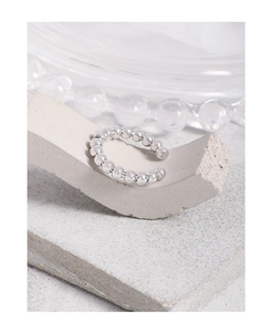 Macro detail of polished S925 sterling silver beaded cuff earring on stone pedestal