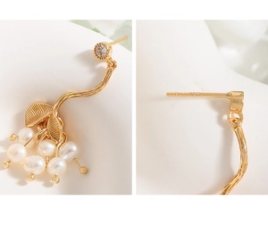 Vue macro de boucles d'oreilles branche dorée avec perles, zircon et poinçon S925