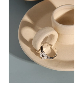 Detail view of a vintage floral pearl ring with black stone center on a ceramic stand