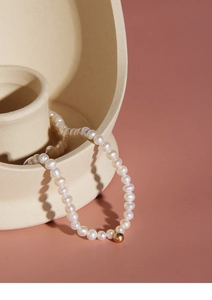 Macro detail of white freshwater pearls and a gold accent bead on a minimalist necklace