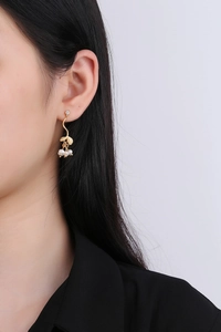 Gros plan de boucles d'oreilles branche dorée avec perles blanches et zircon