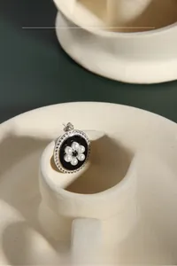 Macro shot of vintage silver earrings with black enamel disc and small white pearl flowers