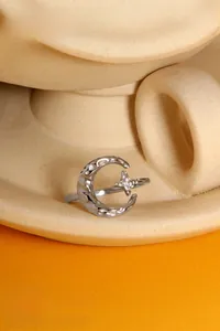 Dettaglio macro dell'anello stella e luna in argento con trama a pieghe e zircone lucido