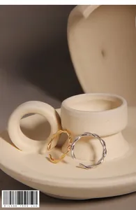 Detail view of minimalist gold and silver twist rings on a ceramic display tray