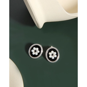 Detail of oval S925 silver stud earrings with black enamel and pearl flower pattern