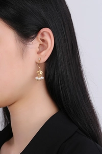 Détail de boucles d'oreilles branche dorée avec perles et zircon portées par un mannequin