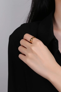 Close-up of minimalist gold interlocking band ring worn by model on black background