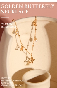 Detailaufnahme der goldenen Schmetterlingskette mit Perle und Blume auf Keramik
