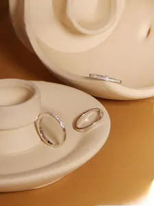 Detailed view of three minimalist S925 silver rings with zircon inlays on ceramic tray