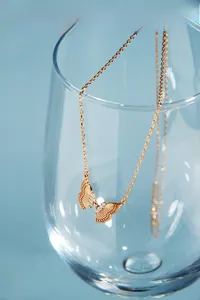 Gros plan d'un collier pendentif papillon en or 18 carats orné de cristaux étincelants