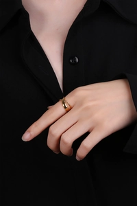 Detailed close-up of a minimalist gold X-shaped criss-cross ring worn on a model's finger