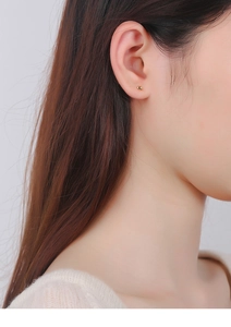 Close-up of a minimalist gold bean stud earring worn on the ear for a daily look