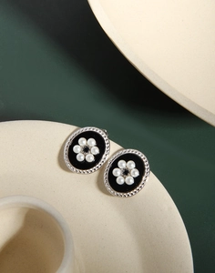 Close-up of retro oval silver earrings with black enamel and small pearl flowers
