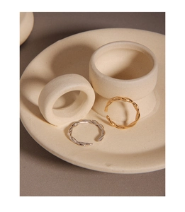 Close-up of gold and silver twisted rope open rings on a white ceramic display tray