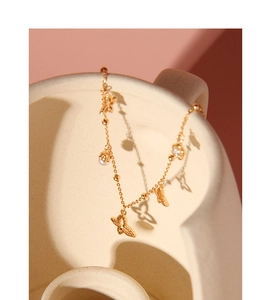 Details einer goldenen Schmetterlingskette mit Perlen und Blumen auf Keramikgefäß