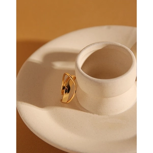 Detail of minimalist gold layered line ring resting on cream ceramic with elegant shadows