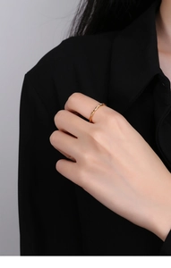 Macro shot of gold twisted rope ring on model's finger with minimalist jewelry design