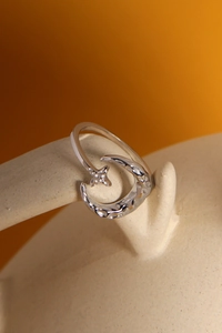 Dettaglio ravvicinato di un anello in argento con luna e stella e finitura martellata
