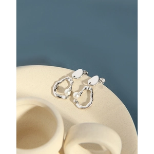 Detail of silver irregular wavy hoop earrings with minimalist white pearls