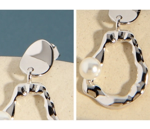 Detail view of silver S925 stud earrings with irregular hammer texture and a white pearl